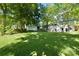 Expansive back yard with lush green grass and large shade trees surrounding the white home at 3549 Woodleaf Rd, Charlotte, NC 28205