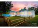 Beautiful home's back exterior boasts fenced yard, white siding, and views of a distant waterfront at 3911 Sandy Point Dr, York, SC 29745