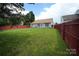 Spacious backyard with a well-maintained lawn, red fencing, and patio at 4037 Lakota Ct, Charlotte, NC 28269