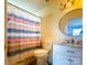 Bathroom features a vanity with marble countertop, circular mirror, toilet, and a shower with a colorful curtain at 4037 Lakota Ct, Charlotte, NC 28269