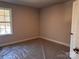 This bedroom has neutral walls, carpet covered in plastic, and a window with a wooded view at 4041 Port Richmond Ave # 9, Gastonia, NC 28056