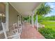 Spacious front porch with brick flooring, rocking chairs, swing, and hanging plants offers a cozy outdoor retreat at 4569 Edgeland Rd, Edgemoor, SC 29712