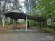 Exterior shot of a large covered carport surrounded by a forest at 490 Deberry Rd, Mount Gilead, NC 27306