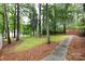 Expansive backyard features grass, mature trees, a deck, and sidewalk at 509 Selkirk Pl, Charlotte, NC 28270