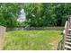 Expansive backyard with a green lawn, wooden fence, and mature trees, plus stairway at 518 Westside Cir, China Grove, NC 28023