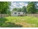 Picturesque backyard with green lawn and surrounding trees, enclosed by a classic wooden fence at 518 Westside Cir, China Grove, NC 28023