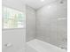 Tiled shower and tub with gray subway tiles plus a window adding natural light to the space at 518 Westside Cir, China Grove, NC 28023