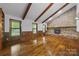 Spacious living room with exposed wood beams, stone fireplace, and hardwood floors at 5200 Winding Ln, Indian Trail, NC 28079