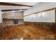 Living room featuring stone fireplace, wood-paneled walls, hardwood floors, and exposed beams at 5200 Winding Ln, Indian Trail, NC 28079