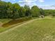 A lush green yard featuring a pond and mature trees at 5200 Winding Ln, Indian Trail, NC 28079