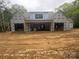 Exterior shot of the back of the home shows its covered patio and dark windows, surrounded by trees and red-dirt filled lot at 5427 Addison Dr, Charlotte, NC 28211
