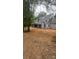Exterior shot of the back of the home shows its covered patio, dark windows and gray roof, surrounded by trees and red dirt at 5427 Addison Dr, Charlotte, NC 28211