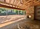The incomplete covered patio features a painted brick fireplace, an exposed ceiling and a view of the backyard and surrounding trees at 5427 Addison Dr, Charlotte, NC 28211