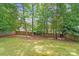 Large backyard with a wooden fence, lush grass, mature trees offering shade, perfect for outdoor enjoyment at 6216 Bandy Dr, Charlotte, NC 28227