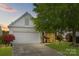 Charming home with a two-car garage, manicured lawn, and lovely landscaping at dusk at 8410 Darcy Hopkins Dr, Charlotte, NC 28277