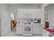 White kitchen featuring white cabinets, a white range, a microwave and white tile flooring at 8410 Darcy Hopkins Dr, Charlotte, NC 28277