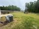 Fenced backyard with a playhouse and swing set, patio with chairs, and an AC unit at 110 Browband St, Troutman, NC 28166
