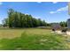 Large, well-maintained backyard with green grass, a wooden fence, mature trees, and a small patio area at 110 Browband St, Troutman, NC 28166