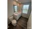 Bathroom with double sinks, wood floors, a toilet, and a window view at 110 Browband St, Troutman, NC 28166