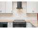Close-up view of the kitchen's range with stainless steel hood and white marble-look backsplash at 1244 Bob Falls Rd, Shelby, NC 28150