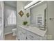 Bathroom with white vanity, decorative mirror, and window for natural light at 129 Renaissance Pl, Statesville, NC 28625