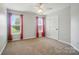 A neutral-toned bedroom featuring plush carpet, a ceiling fan, and bright windows with red curtains at 138 Montibello Dr, Mooresville, NC 28117