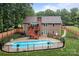 View of the backyard with a pool, brick house, deck, steps, trees, fence, and lawn at 144 Sea Trail Dr, Mooresville, NC 28117