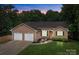 Charming brick home features a two-car garage, manicured lawn, and lush landscaping at 144 Sea Trail Dr, Mooresville, NC 28117