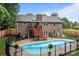 A backyard swimming pool surrounded by black fence, with a two-story brick home and elevated deck at 144 Sea Trail Dr, Mooresville, NC 28117