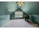 Attic space with slanted teal walls, carpet, a window, and a ceiling fan at 1818 Winfield Dr, Monroe, NC 28110