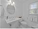 Bathroom with pedestal sink, white fixtures, a round mirror, and natural light from a window at 1818 Winfield Dr, Monroe, NC 28110