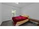 Bedroom with a bed covered with a red blanket, carpet, and natural light at 1818 Winfield Dr, Monroe, NC 28110