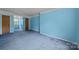 Bedroom with blue walls and carpet, featuring windows for natural light and multiple doors at 1818 Winfield Dr, Monroe, NC 28110