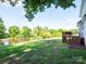 Lush backyard featuring a serene pond view, complemented by a wooden deck, and garden beds at 1918 Gables Dr, Monroe, NC 28112