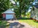 View of the backyard with a detached garage, swing set, mature trees, and a pond at 1918 Gables Dr, Monroe, NC 28112