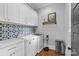Modern laundry room with white cabinets, blue patterned backsplash, and stainless-steel appliances at 2615 Chesterfield Ave, Charlotte, NC 28205