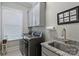 Well-lit laundry room with gray cabinets, sink, and modern washer and dryer at 2630 Mary Butler Way, Charlotte, NC 28226