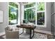 Inviting home office features large windows offering serene wooded views and a workspace designed for comfort and productivity at 301 Riverwood Rd, Mooresville, NC 28117