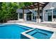 Luxurious pool and jacuzzi with travertine surround and elegant backyard entertaining space at 301 Riverwood Rd, Mooresville, NC 28117