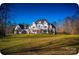 Expansive estate featuring a large lawn, balconies, and a stately facade under a bright blue sky at 450 Greywalls Ln, Iron Station, NC 28080