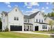 Beautiful two-story white farmhouse with a black garage door and pristine landscaping on a sunny day at 4530 Tournette Dr # 18, Indian Land, SC 29707