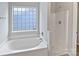 Well-lit bathroom with a soaking tub, separate shower, and tiled window for added privacy at 752 Raindrops Rd, Gastonia, NC 28054