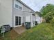 A townhome backyard with green grass, trash receptacles, and an AC unit at 7562 Petrea Ln, Charlotte, NC 28227