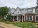 Inviting exterior view of townhomes featuring manicured lawns and covered porches, with a blend of brick and siding facades at 7562 Petrea Ln, Charlotte, NC 28227