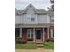 Charming townhome featuring a brick facade, covered porch, and inviting curb appeal with colorful chairs and plantings at 7562 Petrea Ln, Charlotte, NC 28227