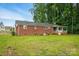 View of the back of a brick home featuring a grassy yard and covered porch at 800 Old Little Rock Rd, Charlotte, NC 28214