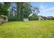 Expansive backyard featuring lush green lawn, mature trees, and a storage shed for outdoor equipment and gardening supplies at 800 Old Little Rock Rd, Charlotte, NC 28214