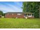 A brick home's backyard featuring a grassy yard and covered porch at 800 Old Little Rock Rd, Charlotte, NC 28214