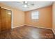 Bedroom with a window and hardwood floors, featuring orange painted walls, a ceiling fan, and closet at 800 Old Little Rock Rd, Charlotte, NC 28214