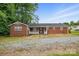 A quaint single story brick home with a white lattice porch and gravel driveway in the front at 800 Old Little Rock Rd, Charlotte, NC 28214